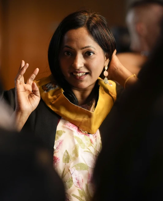 A graduate smiling and adjusting her gown collar among fellow graduates at the Glasgow Kelvin College ceremony. A graduate smiling and adjusting her gown collar among fellow graduates at the Glasgow Kelvin College ceremony.